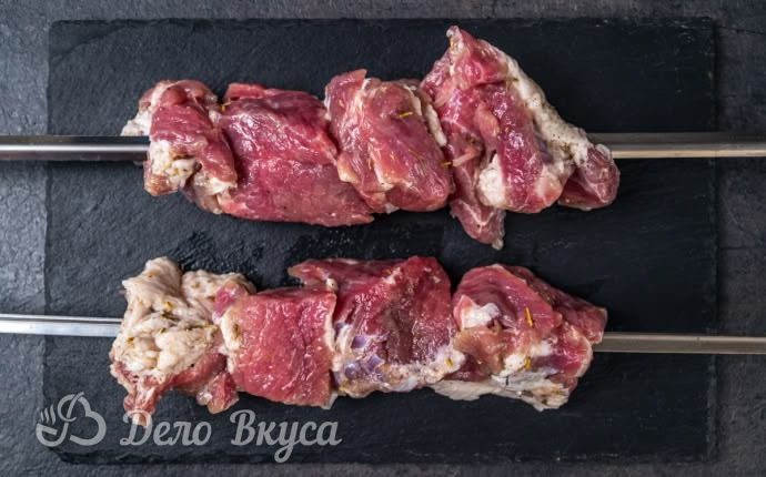 Нанизывание кусочков замаринованной свинины на металлический шампур